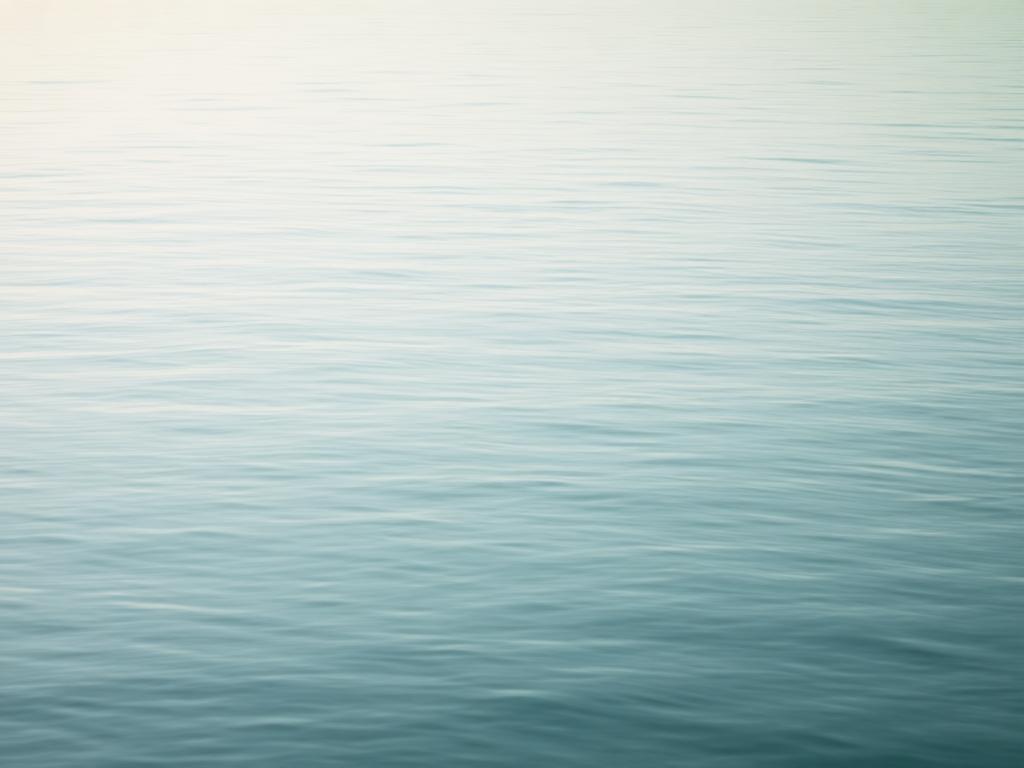 Calm open water at dawn in soft teal light